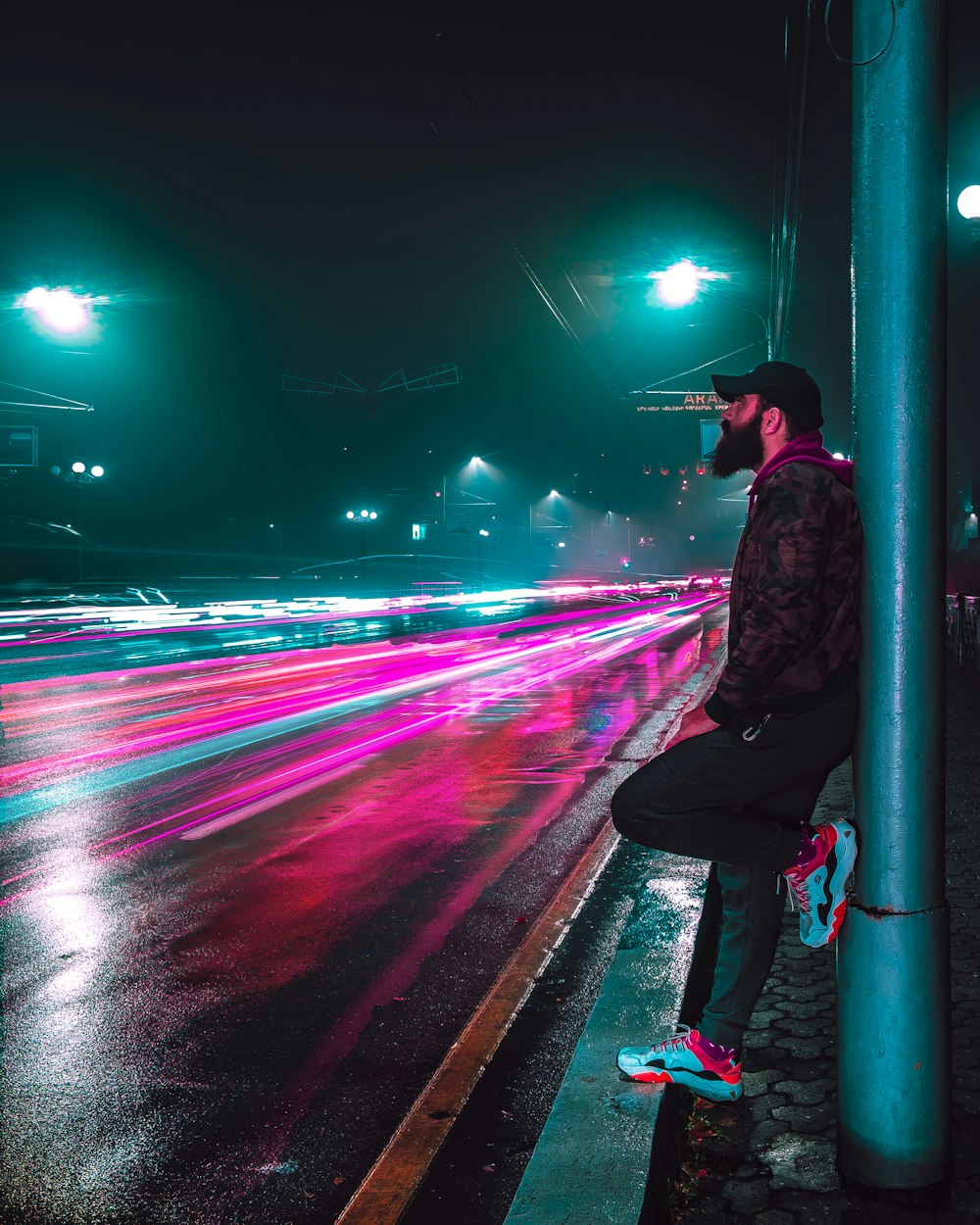 selective focus photography of man leaning on utility pole beside road