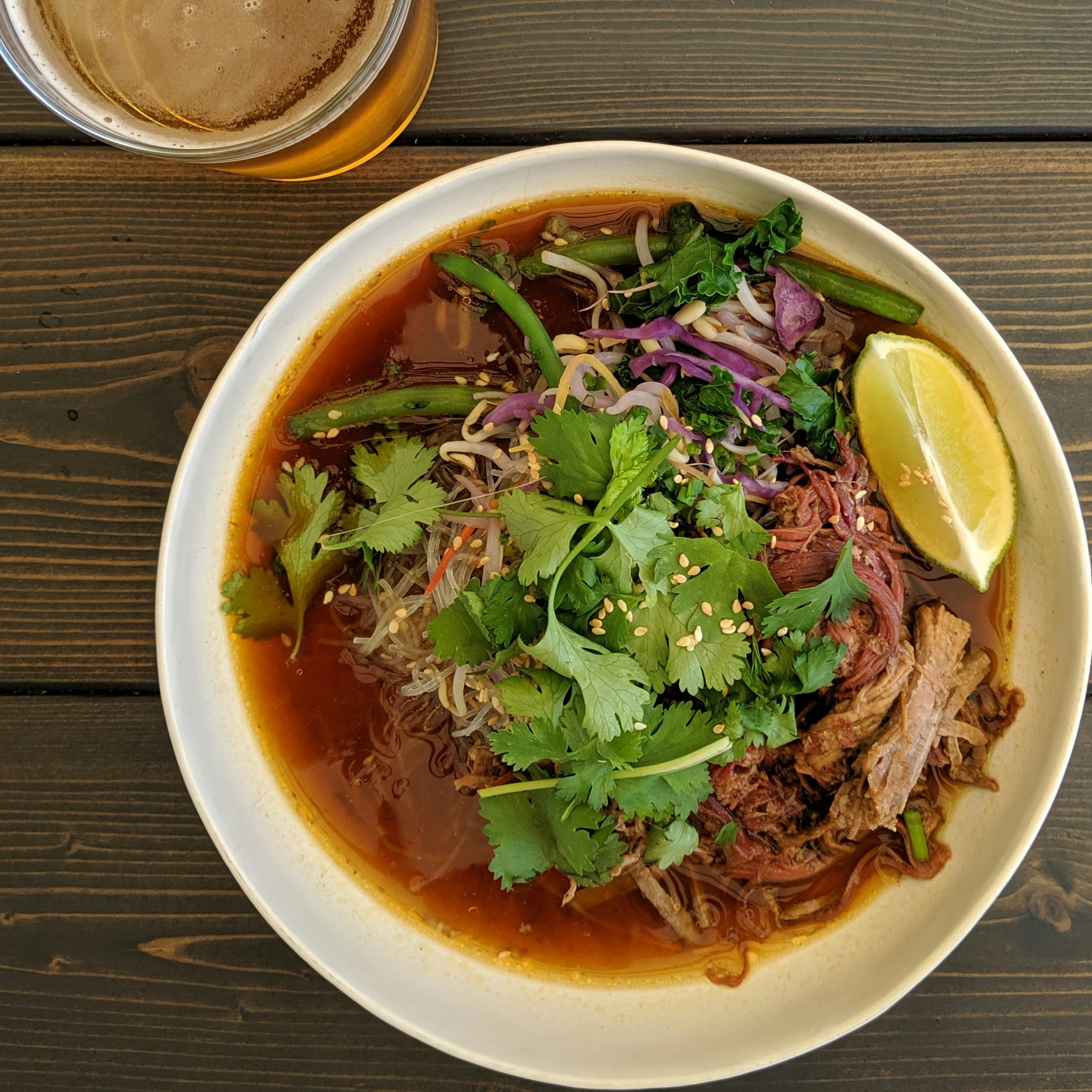 Vietnamese pho bo beef noodle soup with fresh herbs and bean sprouts, bright natural lighting