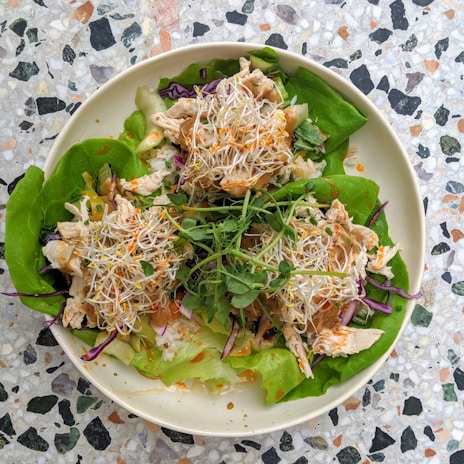 Elegant serving of a green salad with sprouts, artfully arranged on a sleek white plate.