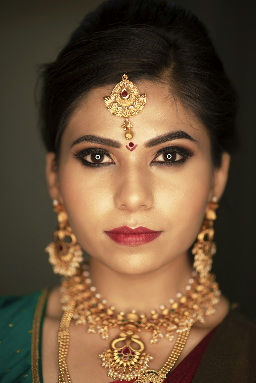 woman wearing gold dangling earrings and necklace