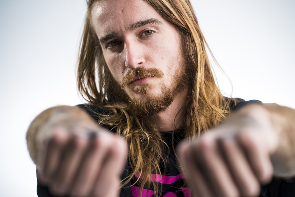 a man with long hair pointing at the camera