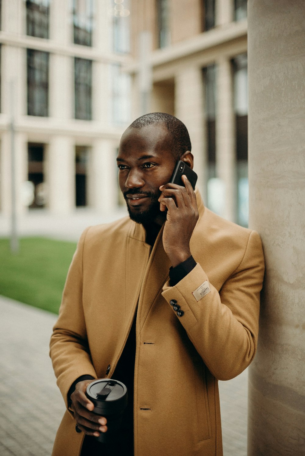 selective focus photography of man talking on phone and holding cup