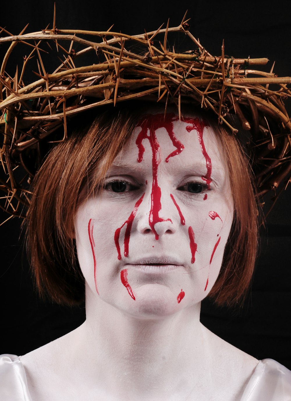 woman wearing white make-up and crown of thorns