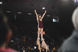 Coed cheer team executing a high-flying stunt with the São Bernardo do Campo venue in the background