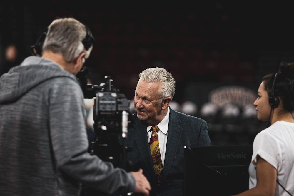 man wearing grey suit beside the video camera