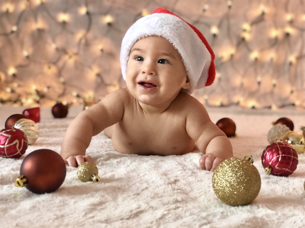 close-up photography of naked baby surrounded by Christmas baubles
