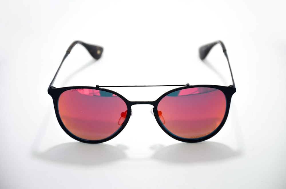 óculos de sol com armação preta na superfície branca