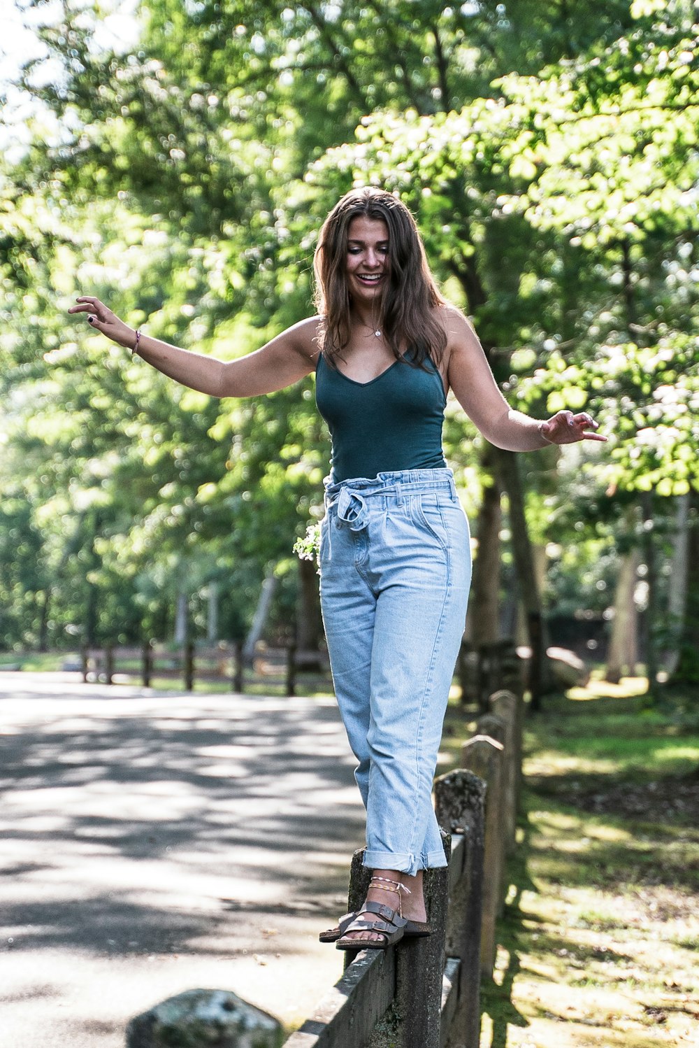 woman walking on wooden fence surrounded by trees during daytime