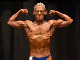 A choreographed posing routine being performed on stage by a muscular athlete.