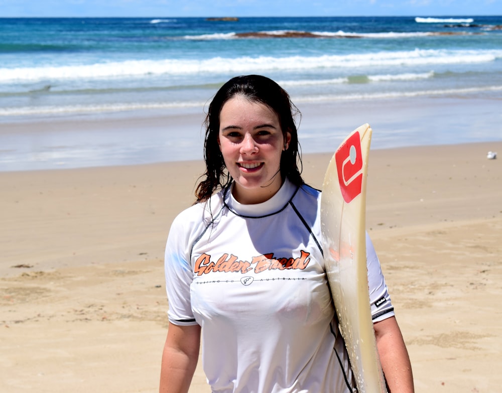 woman wearing white shirt holding surfboard
