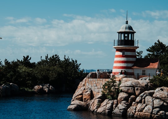 white and red striped lighthouse near body of water in Tokyo DisneySea Japan