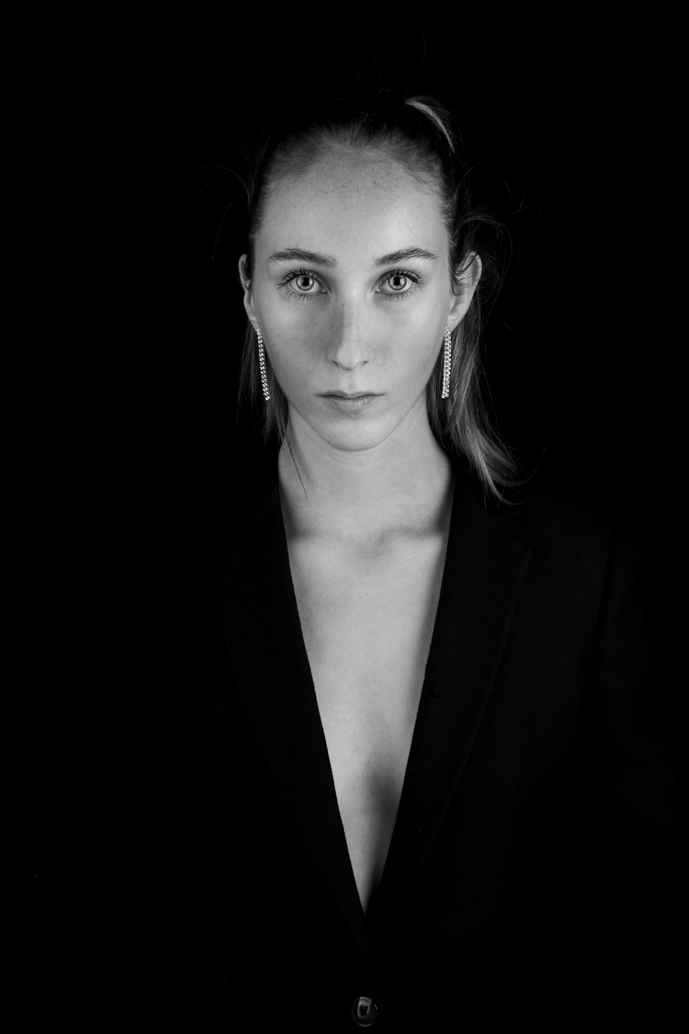 grayscale photography of woman wearing notched lapel suit jacket looking straight