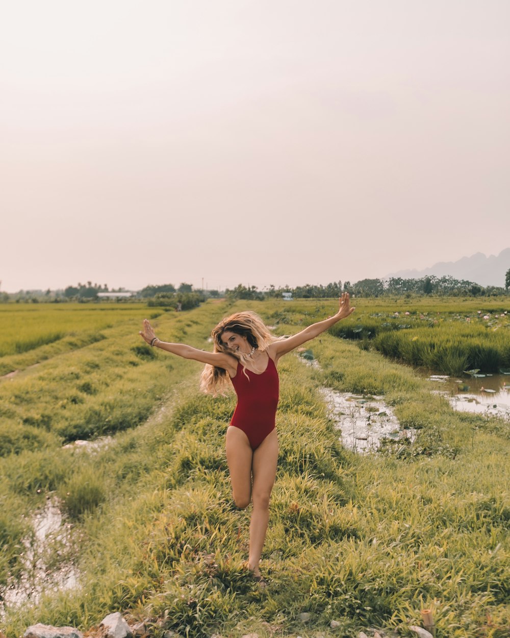 woman running in grass field wearing red swimsuit