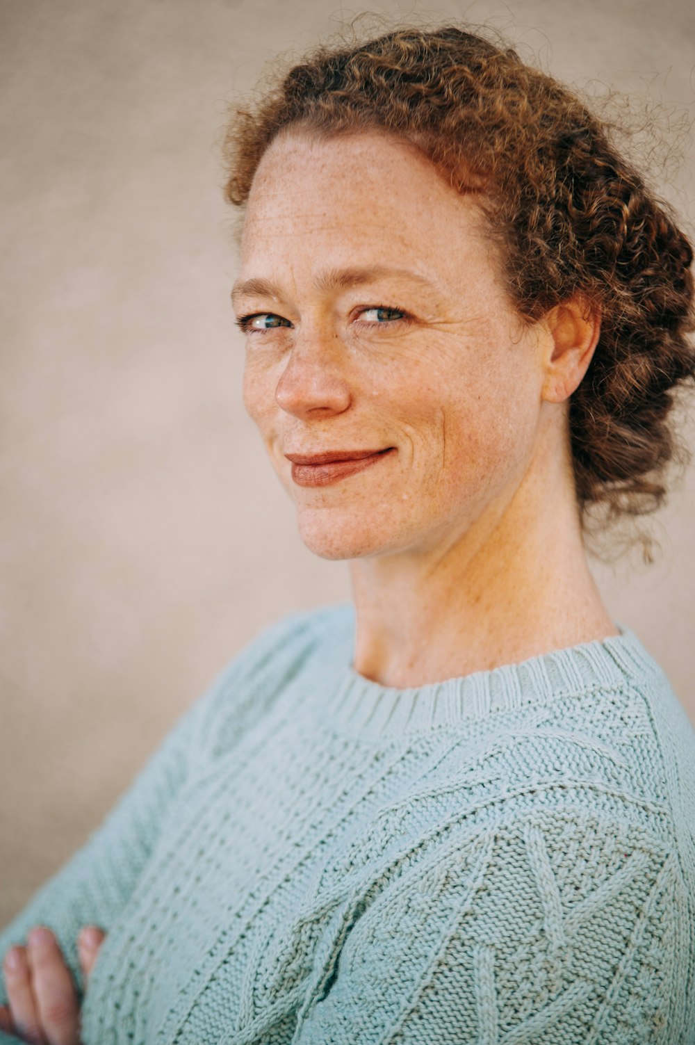 笑顔のティール色のクルーネックセーターを着た女性の肖像写真