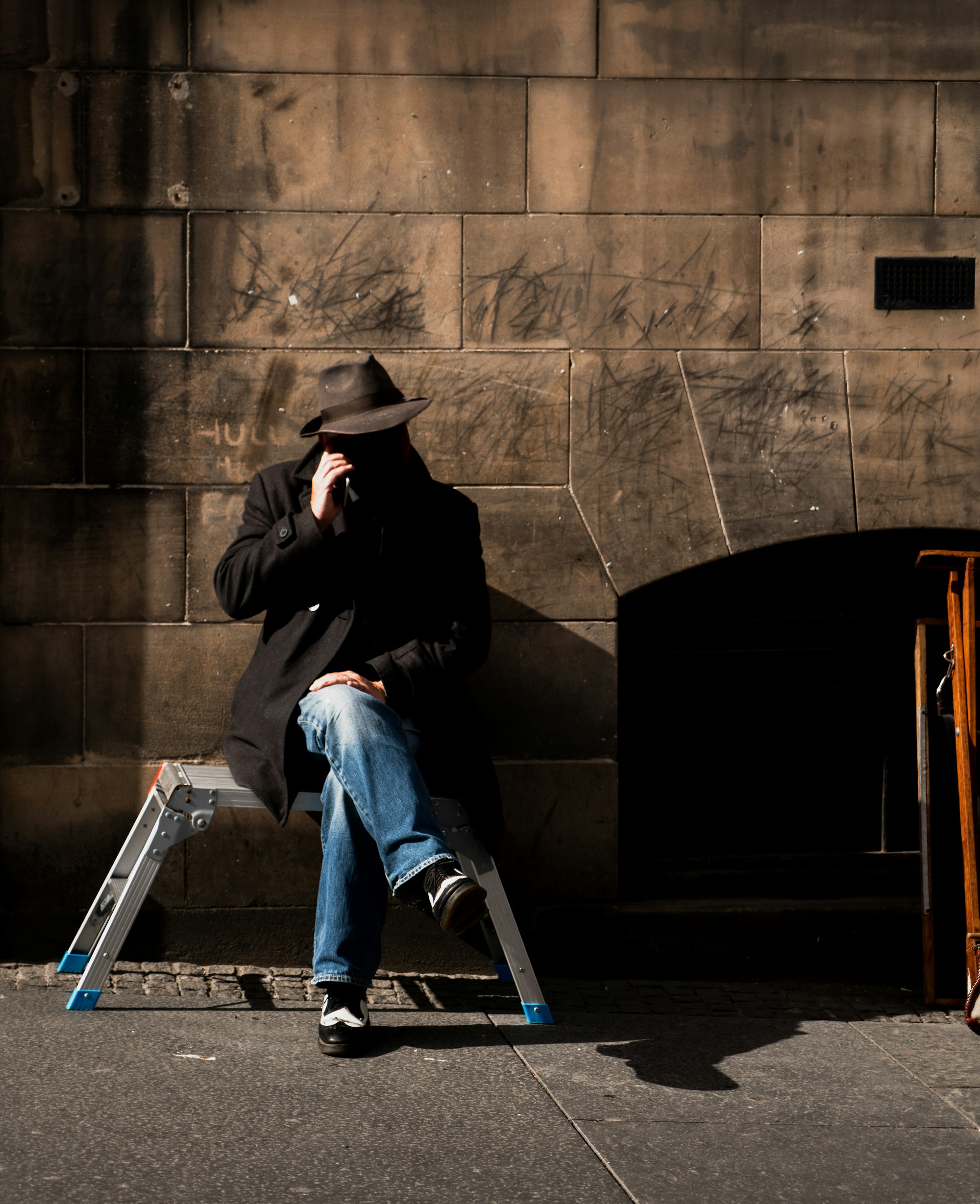 Man on the phone while sitting on the street.