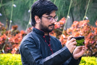 Man wearing a complete African styled outfit chatting on WhatsApp on a smartphone