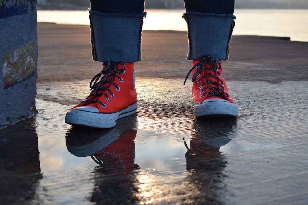 person in red and white nike sneakers standing on wet ground