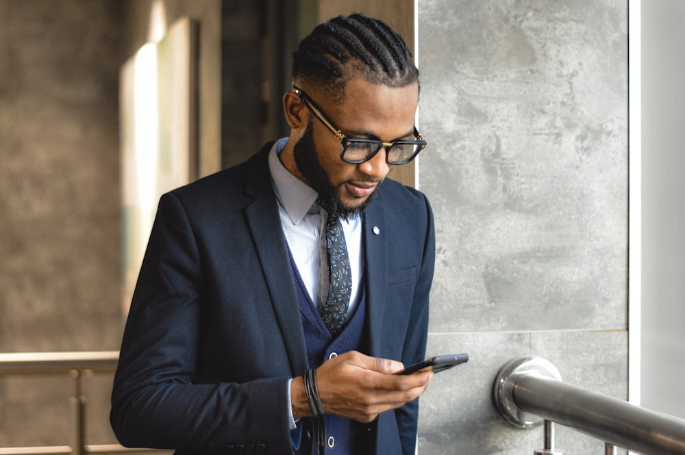 man in blue suit jacket holding smartphone
