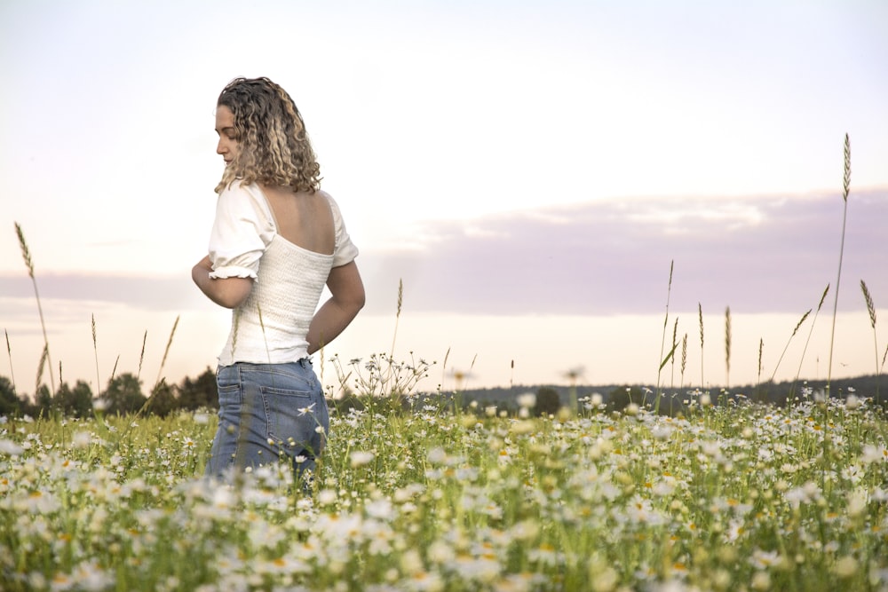 donna circondata da un campo di fiori dai petali bianchi