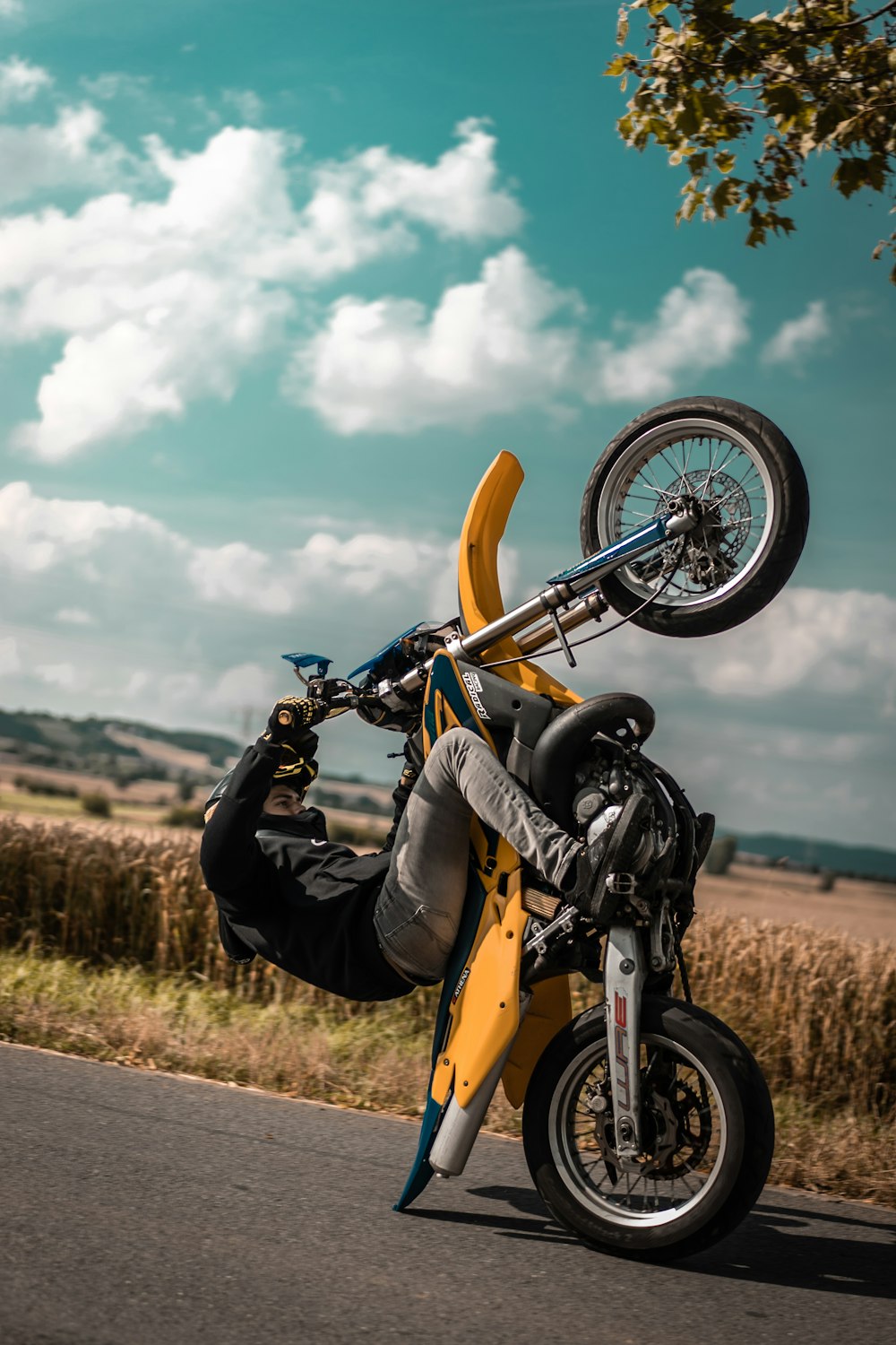 man riding yellow motocross dirt bike on road near grass during cloudy day