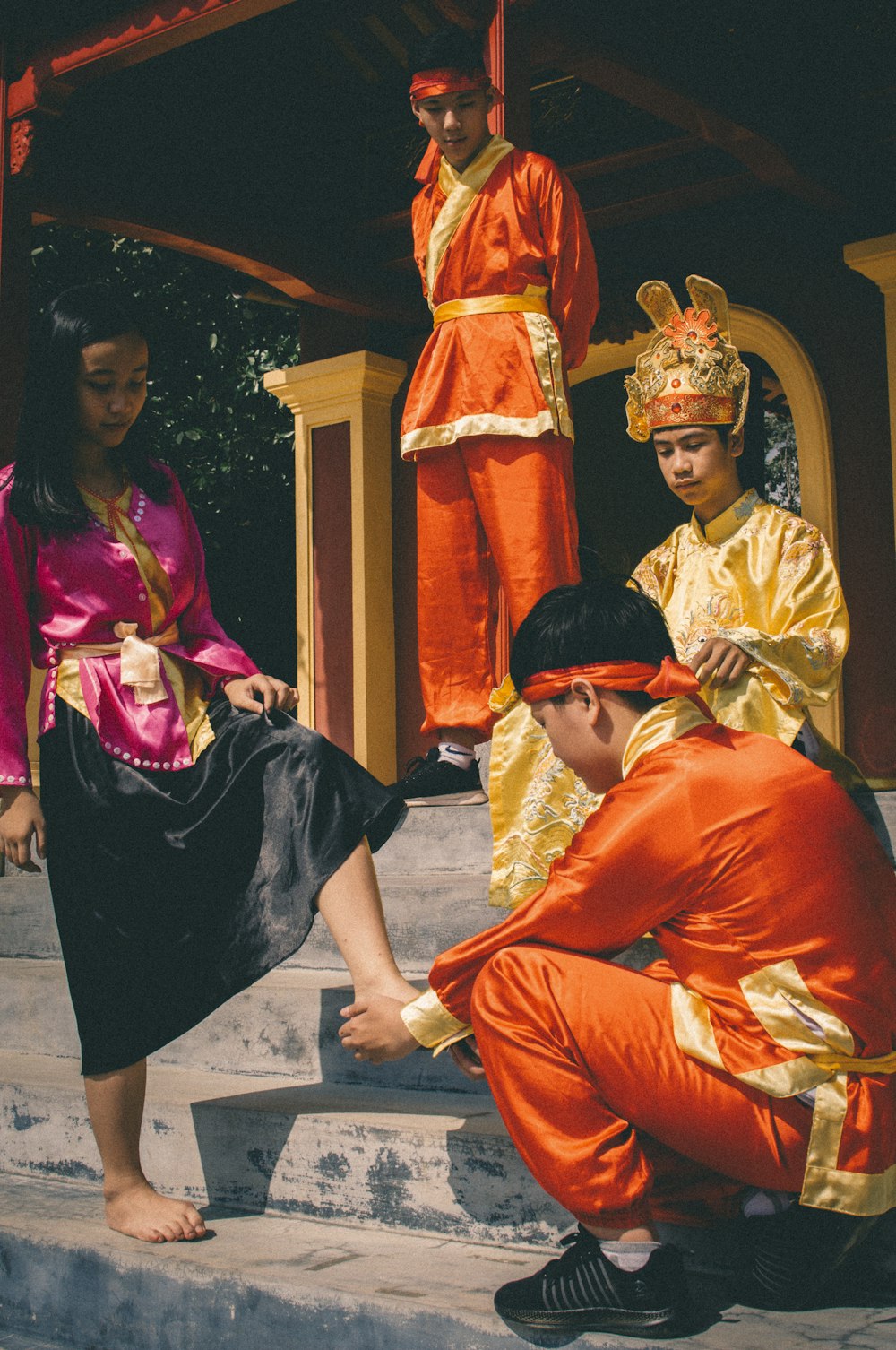 barefooted woman standing and man touching foot of woman in a ceremony and another two people watching them