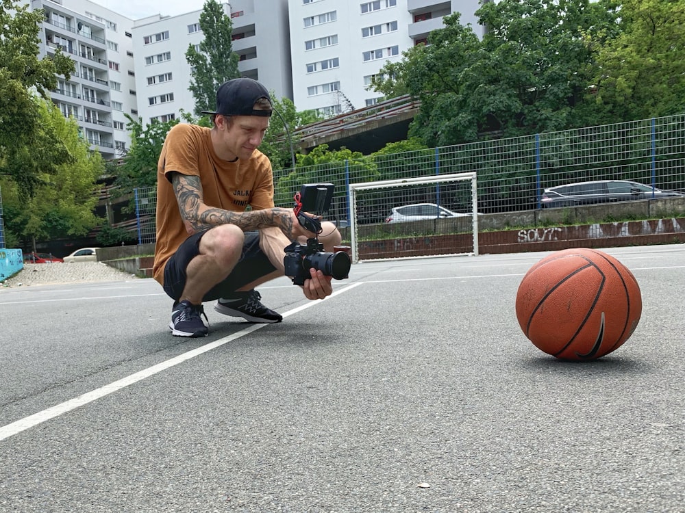 man in brown crew neck t-shirt and black shorts sitting on basketball hoop during daytime