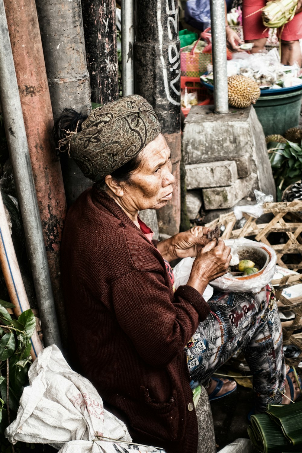 woman wearing brown jacket sitting near wall