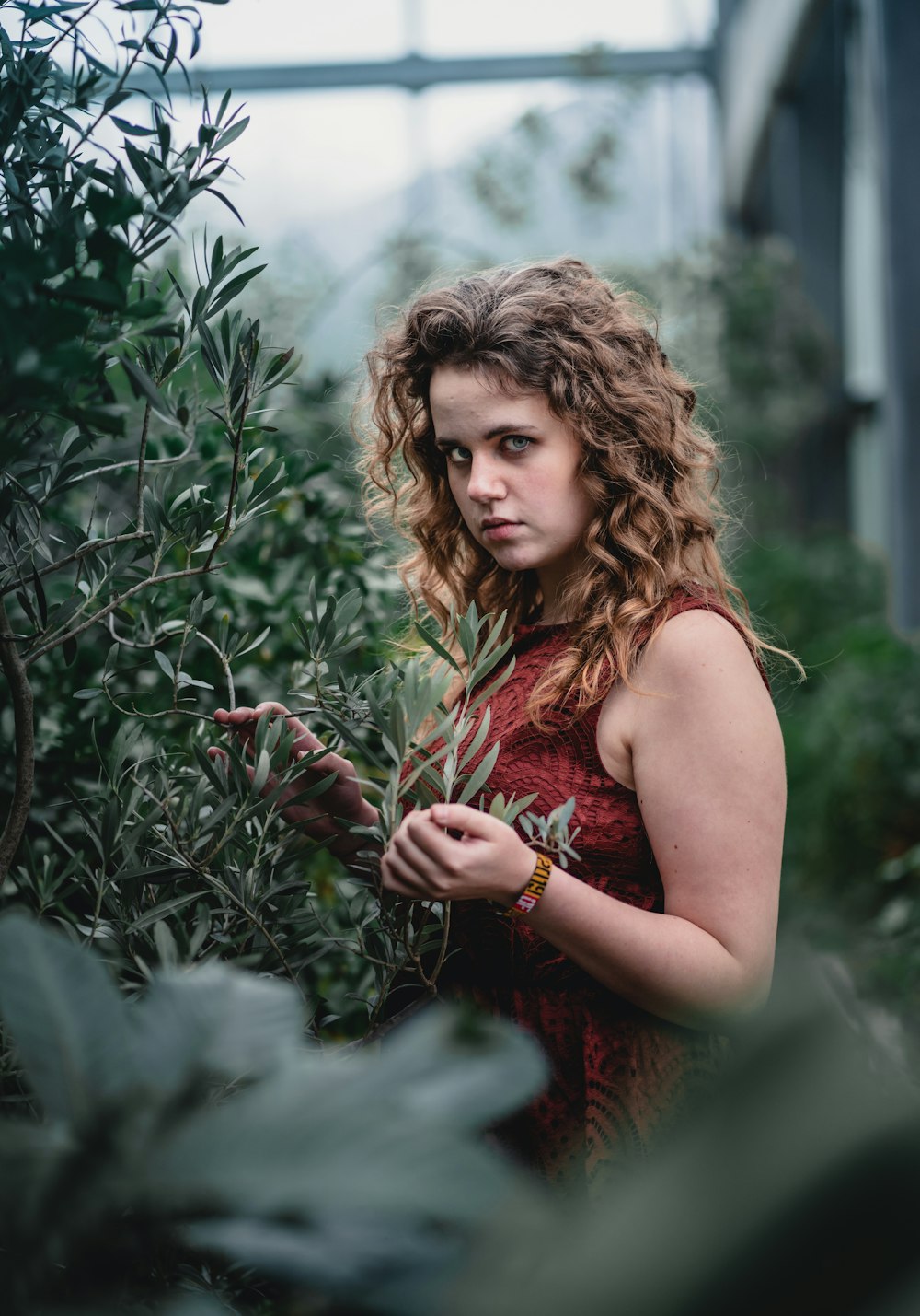 woman wearing red sleeveless dress standing beside plants