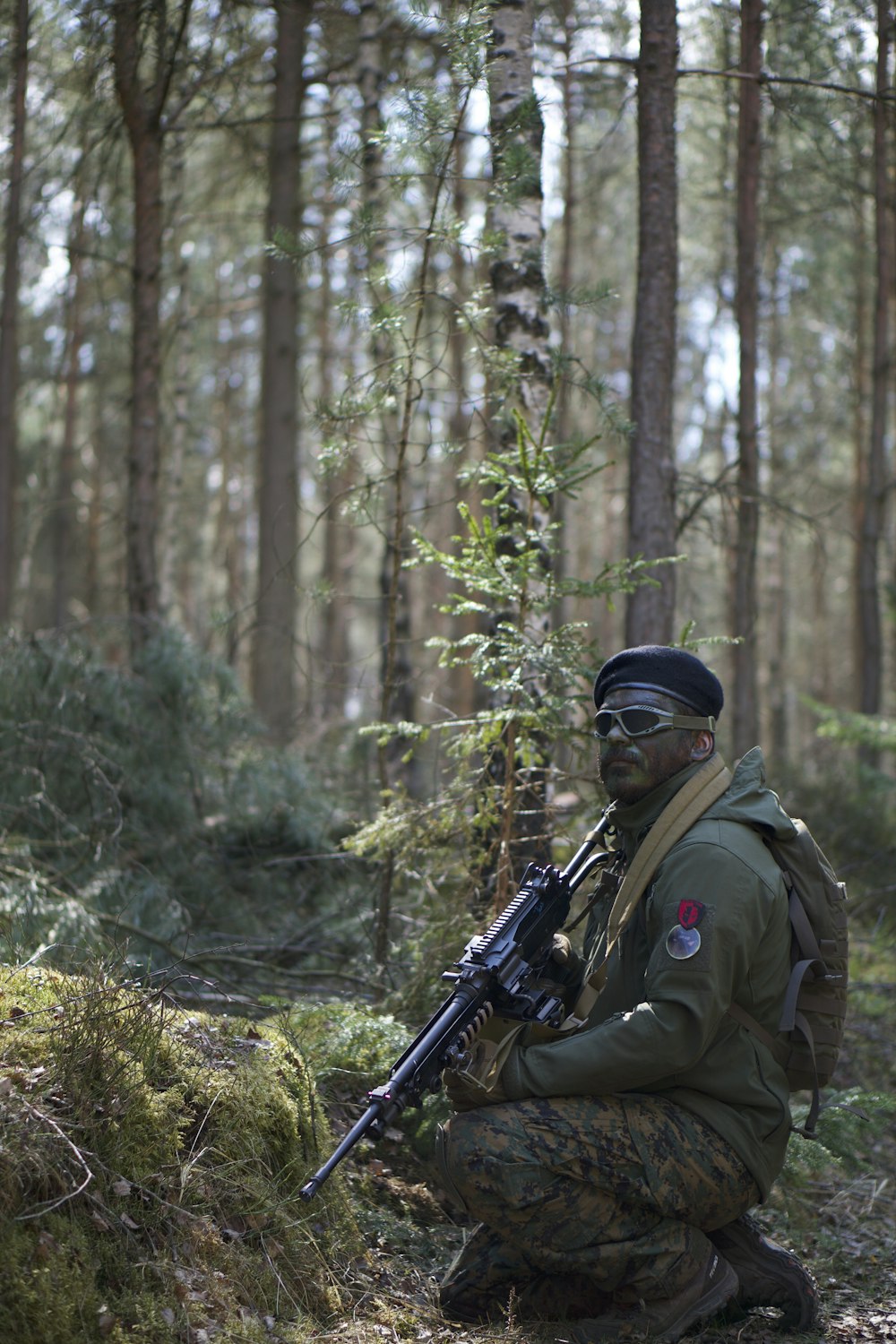 man in uniform holding assault rifle at forest during daytime