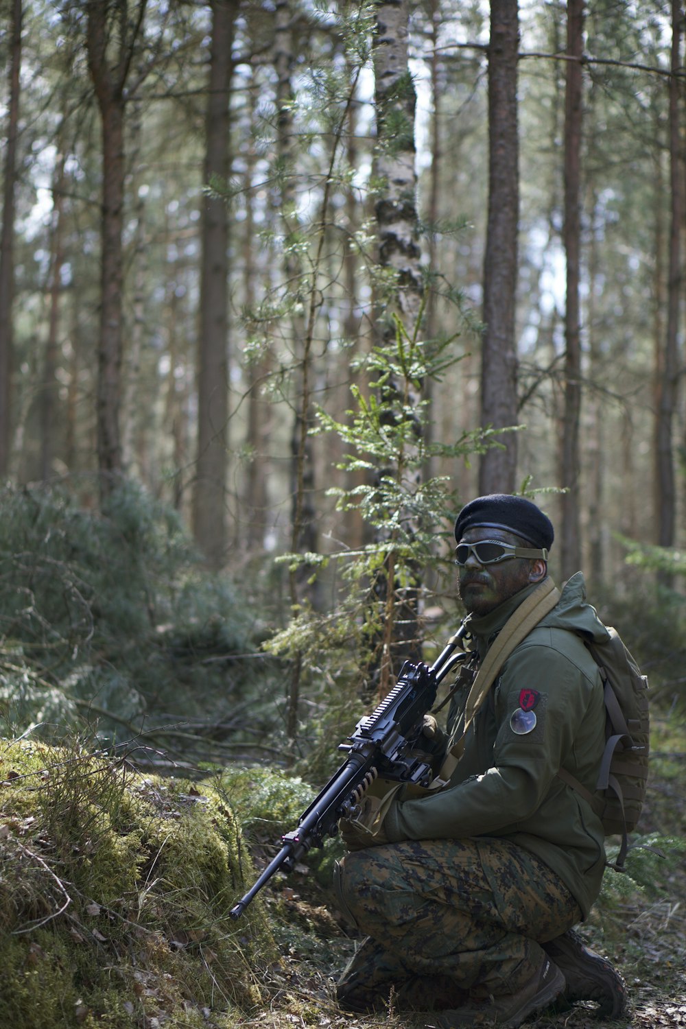 昼間、森でアサルトライフルを構える制服姿の男