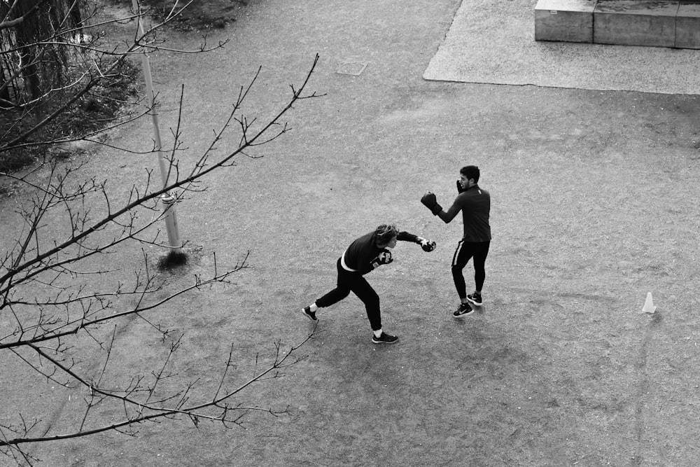 Graustufenfotografie von zwei Menschen, die auf dem Feld boxen