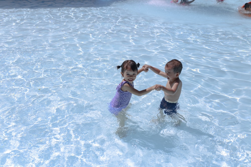 niña y niño jugando en la piscina durante el día