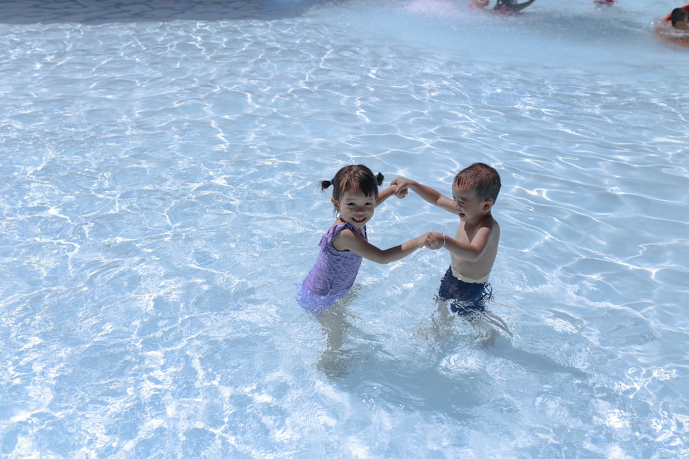 girl and boy playing in swimming pool during daytime