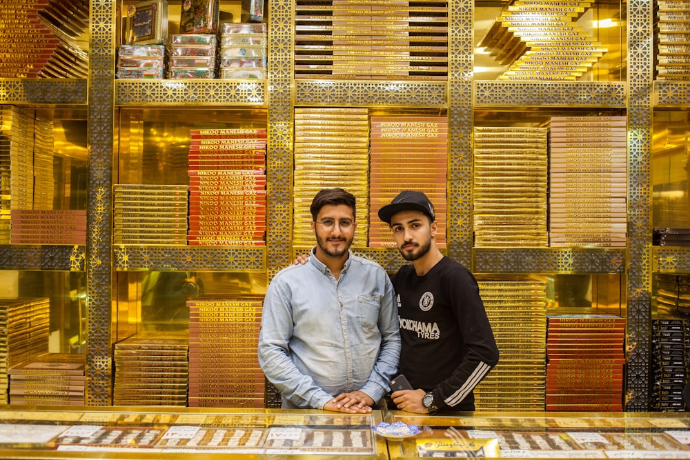 two men standing beside pile of gold bars