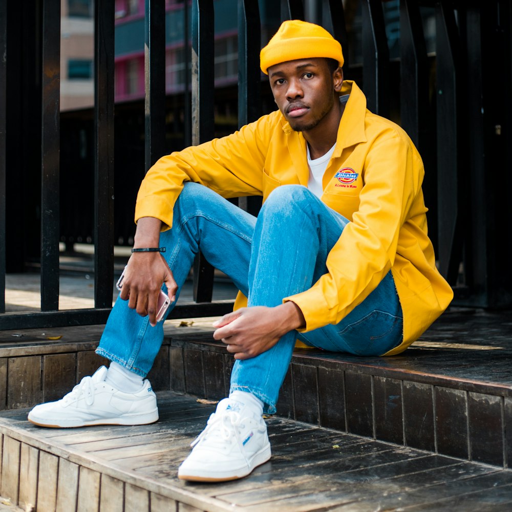 selective focus photography of sitting man wearing yellow jacket