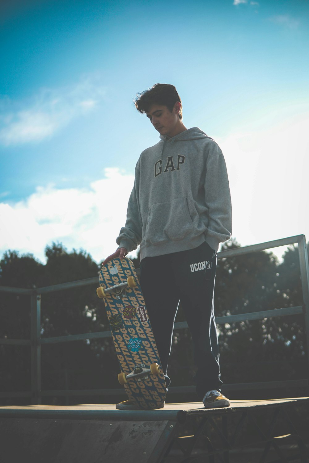 man in gray hoodie holding skateboard