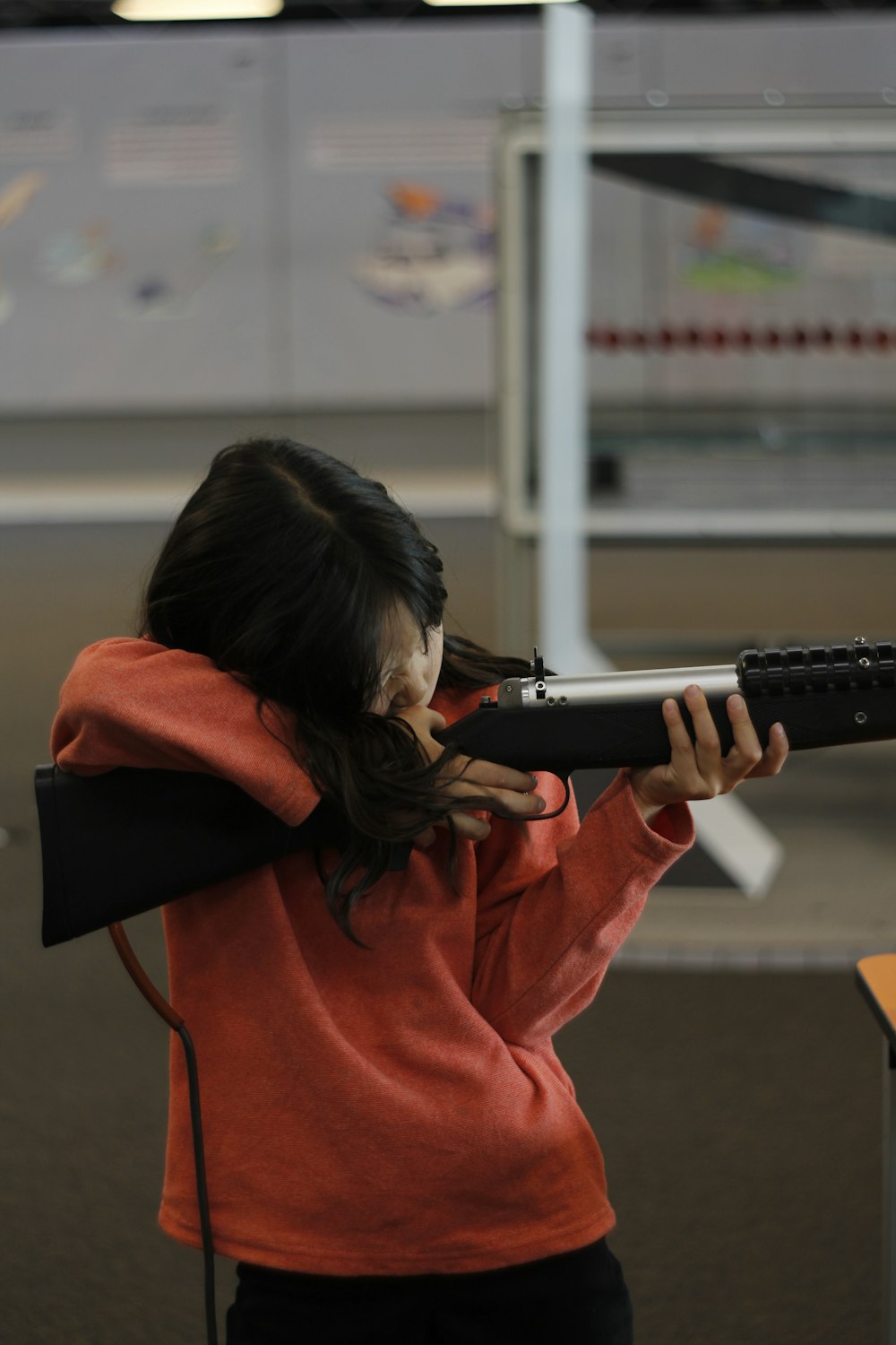 woman in red hoodie holding rifle