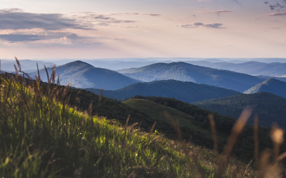 landscape photography of green field viewing mountains under white and gray sky