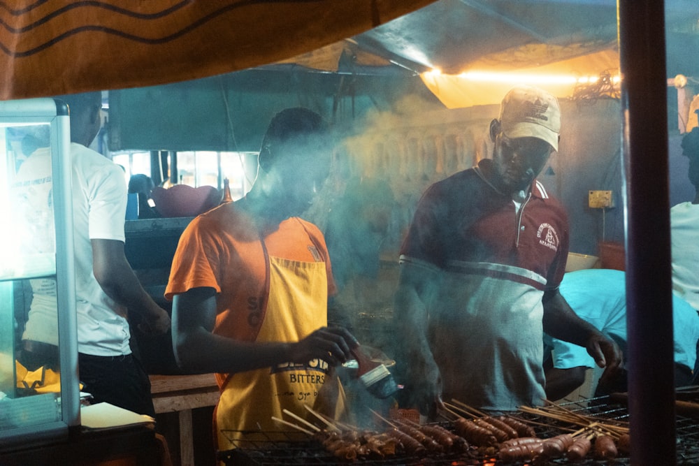 man brushes grilled skewers food beside man