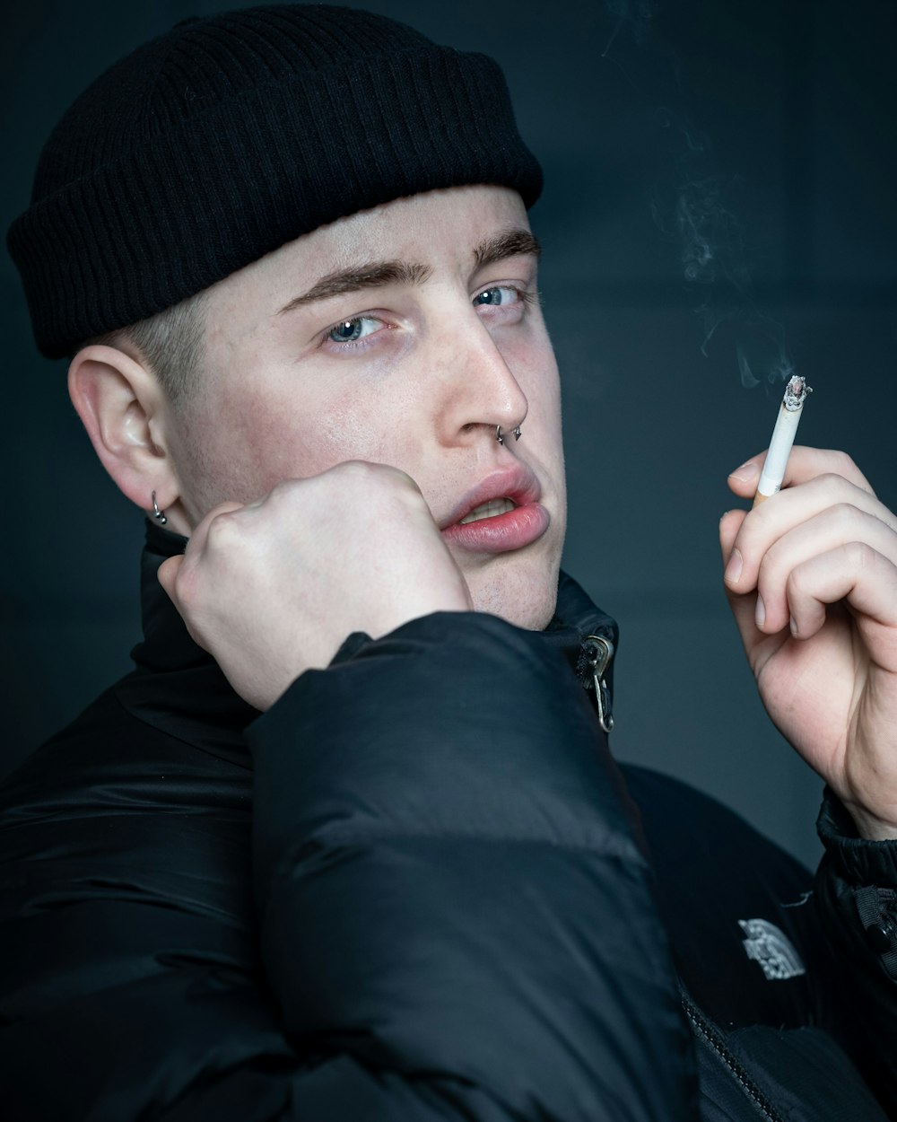 man wearing black jacket holding cigarette stick