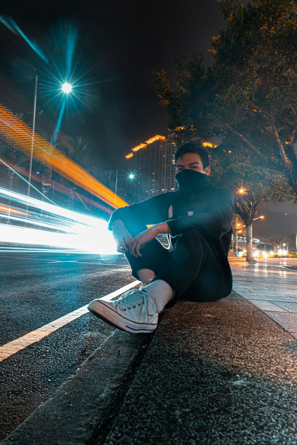 timelapse photography of man in black outfit sitting by side of road