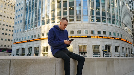 man holding smartphone in Reuters Building United Kingdom