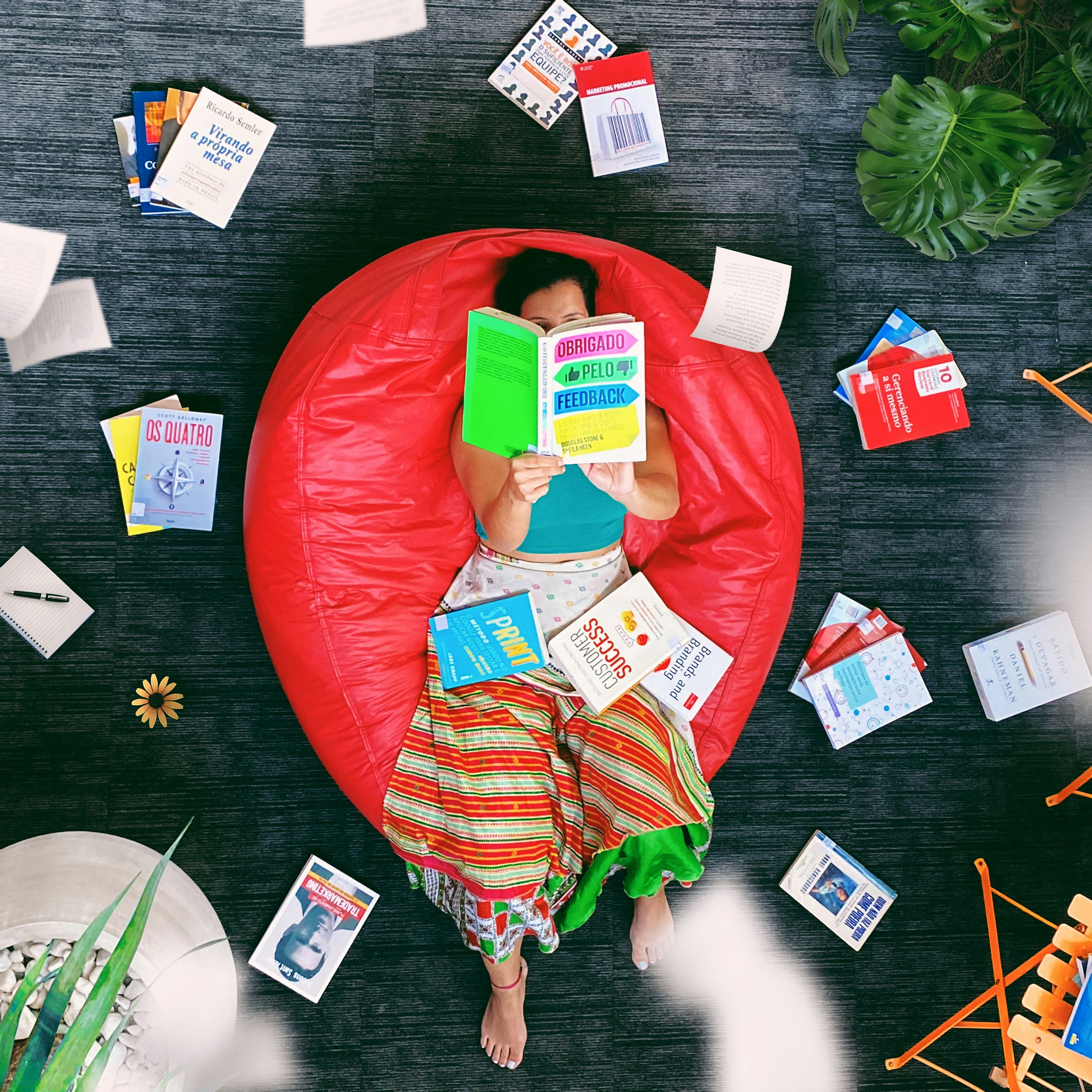 woman lying on red beanbag chair reading book