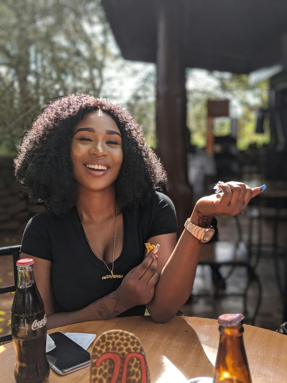 smiling woman wearing black scoop-neck top sitting in front of brown wooden table