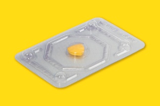 A single yellow pill is encased in a transparent blister pack made of plastic or foil. The background is a solid bright yellow, emphasizing the pill and its packaging.