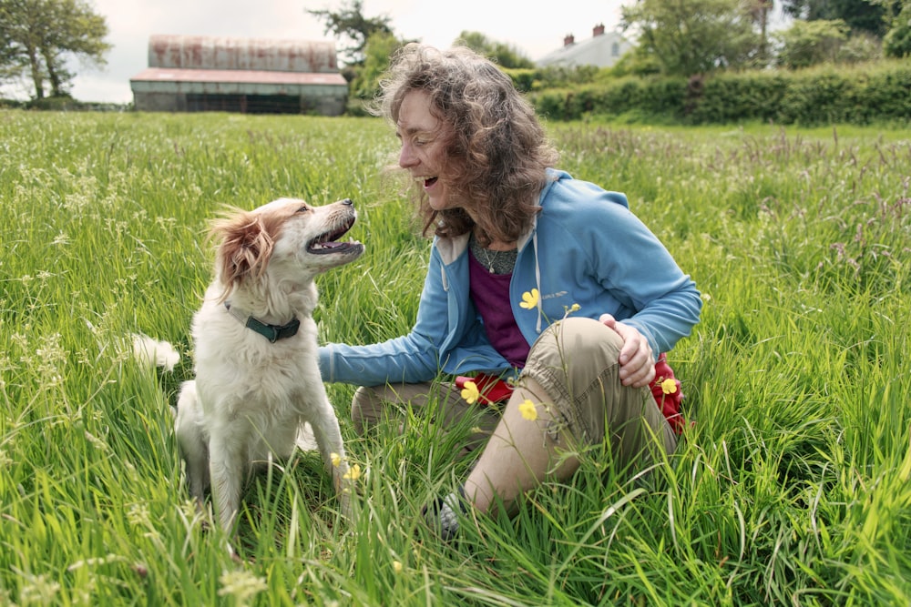 woman sitting beside sitting dog on grass during day