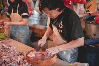 A friendly Carnexa team member inspecting fresh cuts of meat in a bright, clean facility.