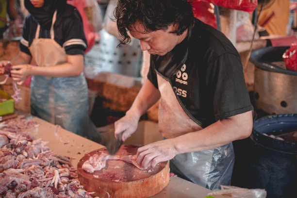 A professional inspecting meat products in a modern processing facility.