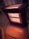 A portable electric heater with visible glowing heating elements is positioned on a polished floor. The heater is plugged in with a black cord extending from it. Ornate furniture and decorative molding can be seen in the background, adding to the cozy indoor atmosphere.