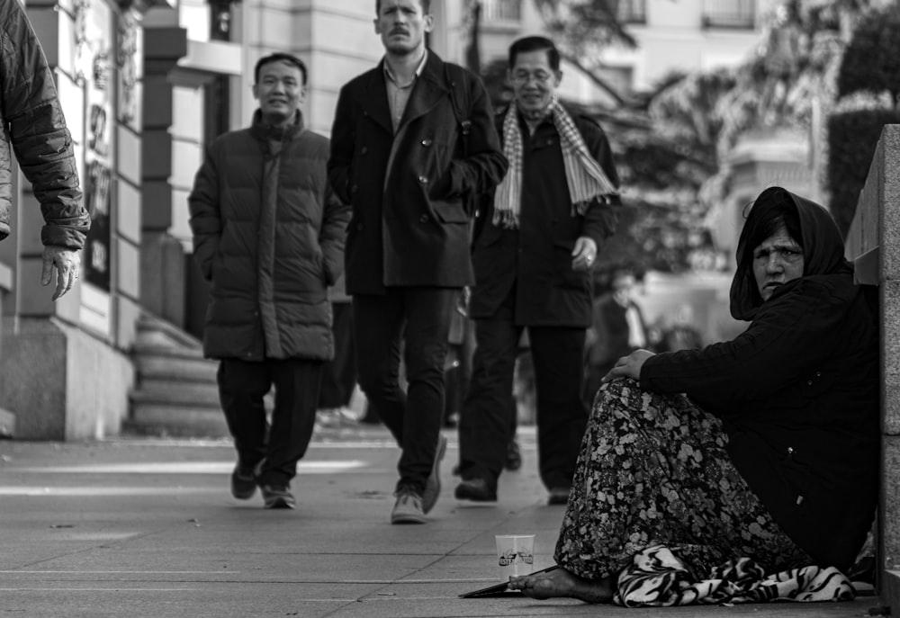 man and woman standing on sidewalk in grayscale photography